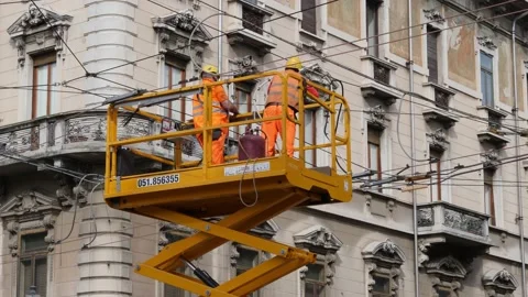 Two Workers with Helmet on Top of a Forklift Working on the Overhead Cables Stock Footage 152454064
