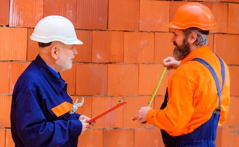 Two workers with helmets and builder uniform in construction site. Profession 写真素材
