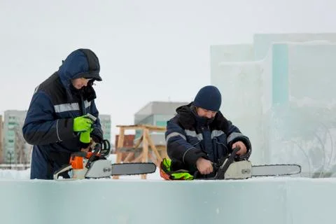 Two workers inspect chainsaws before starting work 写真素材