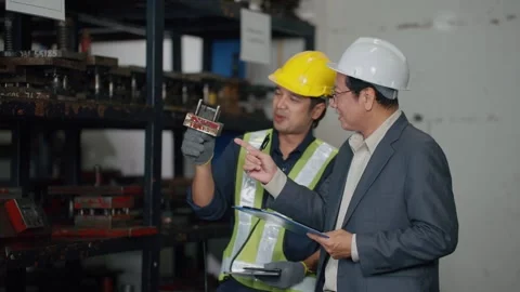 Two workers inspect metal dies in a warehouse 库存影片 341650900