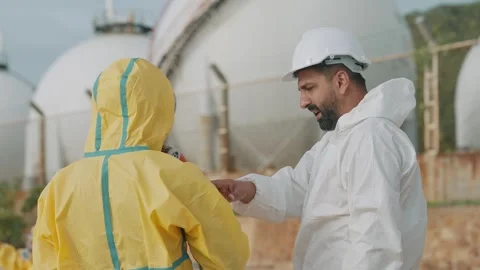 Two workers inspect storage tanks outdoors Stockbeeldmateriaal 343333987