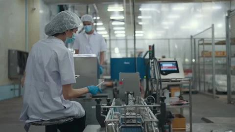 Two workers inspecting of an automated conveyor machine in food production line. Video stock 329538673