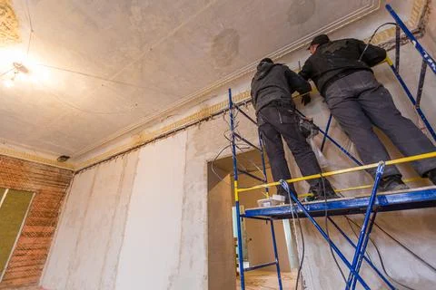 Two workers is installing the electrical wires on the wall that is the part of Stock-Fotos