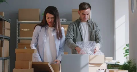 Two workers at Internet store warehouse are packing goods in boxes before 動画素材 276503698