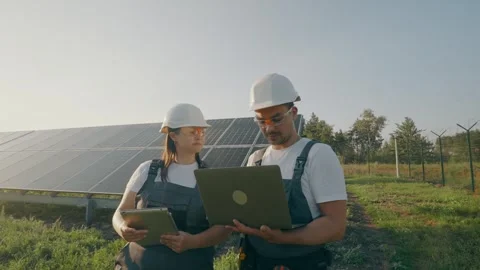 Two workers with a laptop discuss the installation and efficiency of solarpanels Stock Footage 261155593