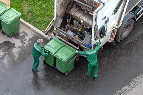 Two workers loading mixed domestic waste in waste collection truck Fotos Stock
