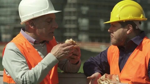 Two workers on a lunch break chatting eating a sandwich Stock Footage 72373438