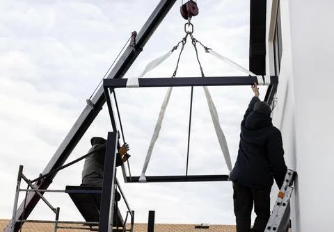 Two workers maintain a crane at a construction site Foto stock