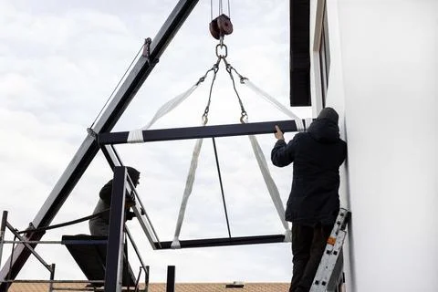 Two workers maintain a crane at a construction site Stock Photos