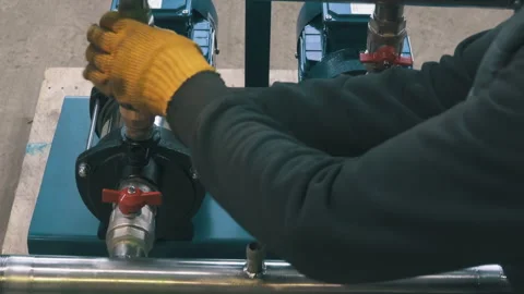 Two Workers Mounting Water Pumps on Steel Frame | Technicians Assembling Pump Stock Footage 343804881