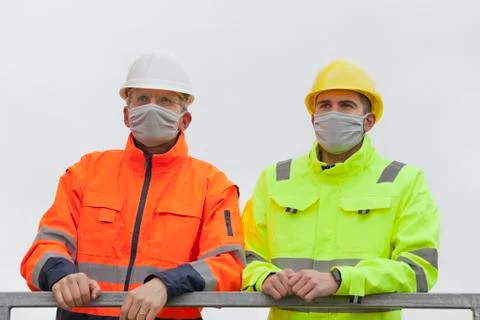 Two workers or engineers with face mask standing on a construction site or  a Stock Photos
