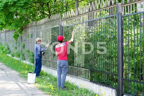 Two Workers Painting a Metal Fence Stock Photos
