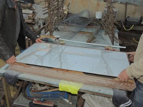 Two workers placing large marble effect tile Stock Photos