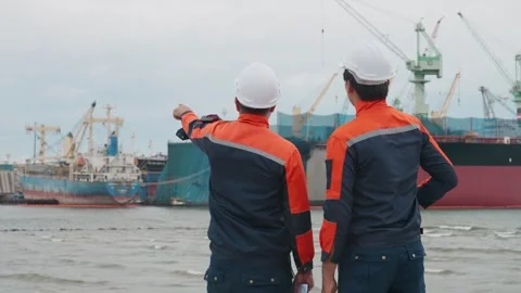 Two workers point toward a large cargo ship Stock Footage 343333380