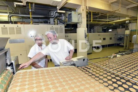 Two Workers At Production Line With Cookies In A Baking Factory