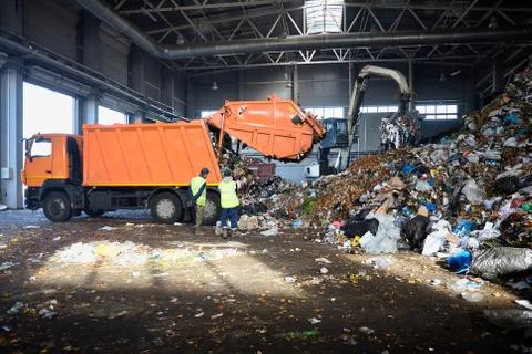 Two workers of recycling plant control process of unloading garbage from garb Stock Photos
