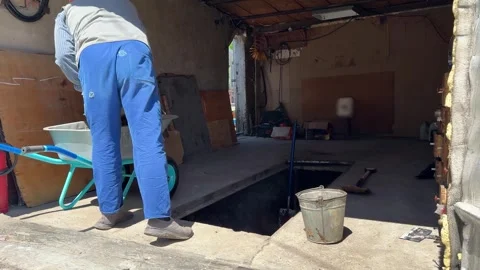 Two workers removing soil from vehicle inspection pit inside garage workshop 库存影片 337989781