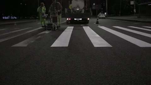 Two workers renovate road markings on asphalt at night medium shot Stock Footage 221925343