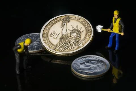 Two workers rescuing a one dollar coin concept of inflation miniature people  Stock Photos