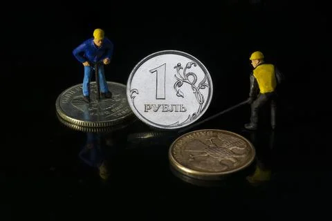 Two workers rescuing a one russian ruble coin concept of inflation in Europe  Stock Photos