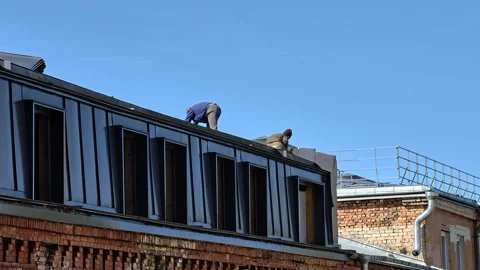 Two workers on a rooftop, constructing or repairing a building Stock Footage 344894097