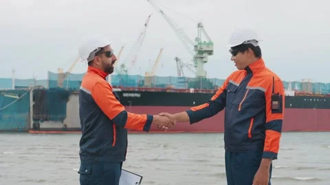Two workers shake hands by a harbor 스톡 동영상 343333379