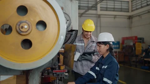 Two workers stand beside heavy machinery in a factory Stock Footage 340271114