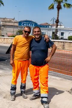Two workers standing roadside in Taranto, Italy Photos