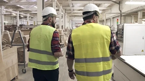 Two workers talking in green waistcoats and helmets at a furniture factory among Stock Footage 88963770