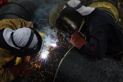Two workers together welding big tube for city heating Stock Photos