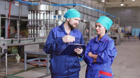 Two workers in uniform in a factory discuss Stock Footage 95794918