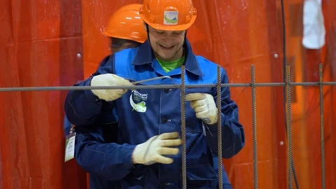 Two workers in uniforms, gloves, hard hat, install metal construction at factory Stock Footage 126357495