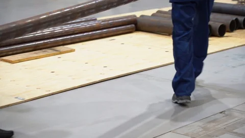 Two workers wear suits, gloves carry long, heavy, rusty pipe, place it on floor  Stock Footage 126355597