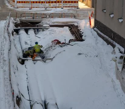 Two workers welding on a big pipe among the snow in a urban construction site Stock-Fotos