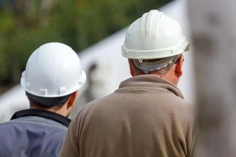 Two workers in white hard hats stand together Stock Photos