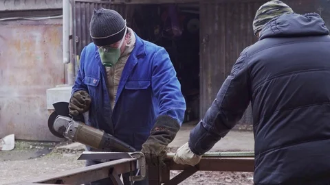 Two workers working with a grinder with a metal structure closeup Stock Footage 102173993