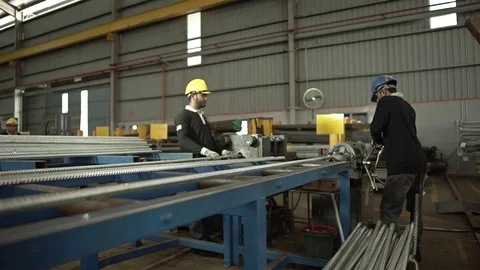 Two Workers Working On A Machine Cutting Silver Pipes - Slider - Towards Stock Footage 79083472