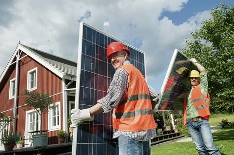 Two workmen installing solar panel house Stock Photos