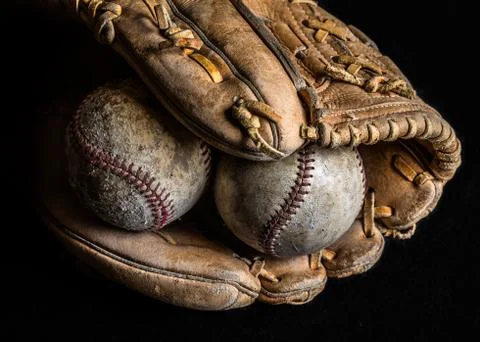 Two worn baseballs in an old mitt on black background. Foto stock