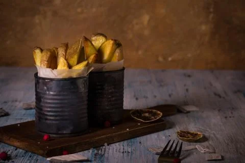 Two worn cans with fried potato stripes on chopping board Stock Photos