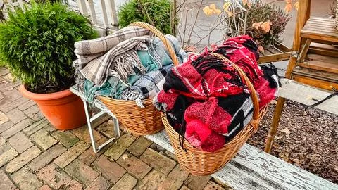 Two woven baskets filled with warm, cozy plaid blankets on a rustic outdoor.. Stock Photos