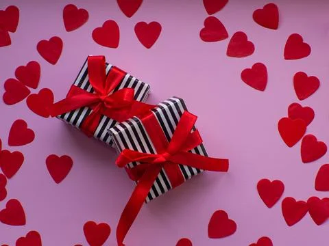 Two wrapped gift boxes are on red heart paper background Stock Photos
