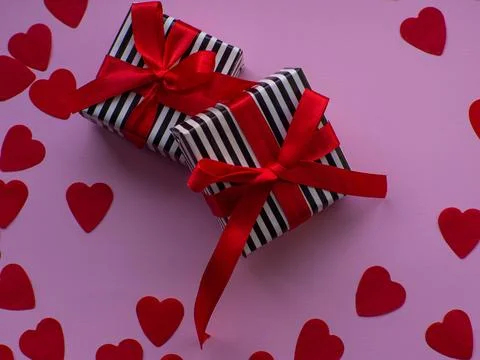 Two wrapped gift boxes are on red heart paper background Stock Photos