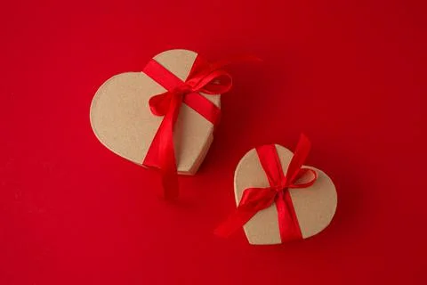 Two wrapped gift boxes in heart shape on red background, Saint Valentine Day Stock Photos