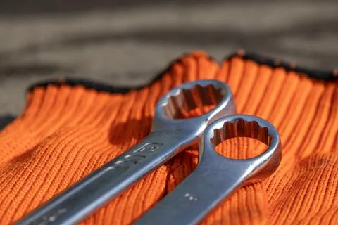 Two Wrenches Placed on an Orange Work Glove in a Well-Lit Area During the D.. Stock Photos
