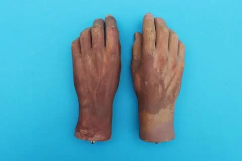 Two wrists from a human hand from a large doll on blue background. Stock Photos