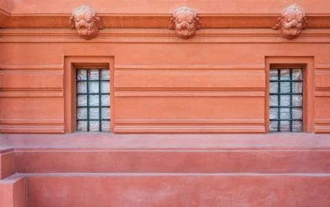 Two wrought iron grid windows in ornamental wall outside of old stone building Stock Photos