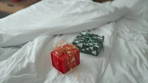 Two xmas surprise present gift covered in paper on crumpled white bed sheets. Stock Footage 297702927