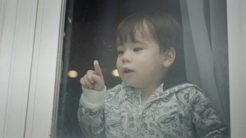 A two-year-old Azait boy looks out of the window, emotionally points his finger Stock Footage 166079588