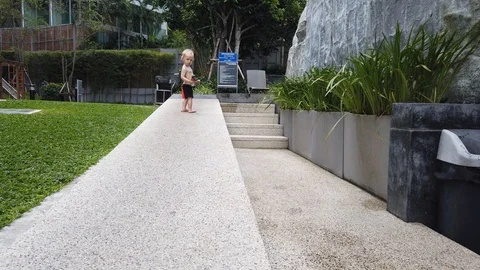 Two-year-old blond boy with a toy in his hand running on a granite path. Stock Footage 104702514